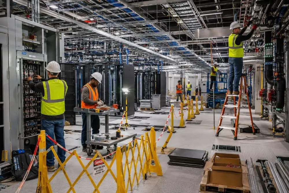 Workers installing electrical and mechanical systems inside an active data center construction site